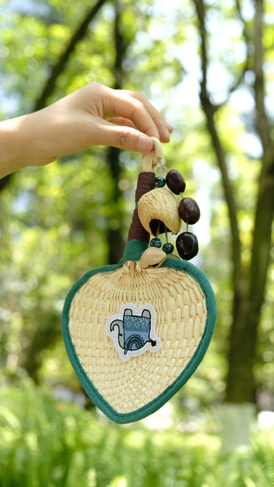 The Lucky Breeze - Hand-Woven Heart Palm Fan with Blue Elephant Charm