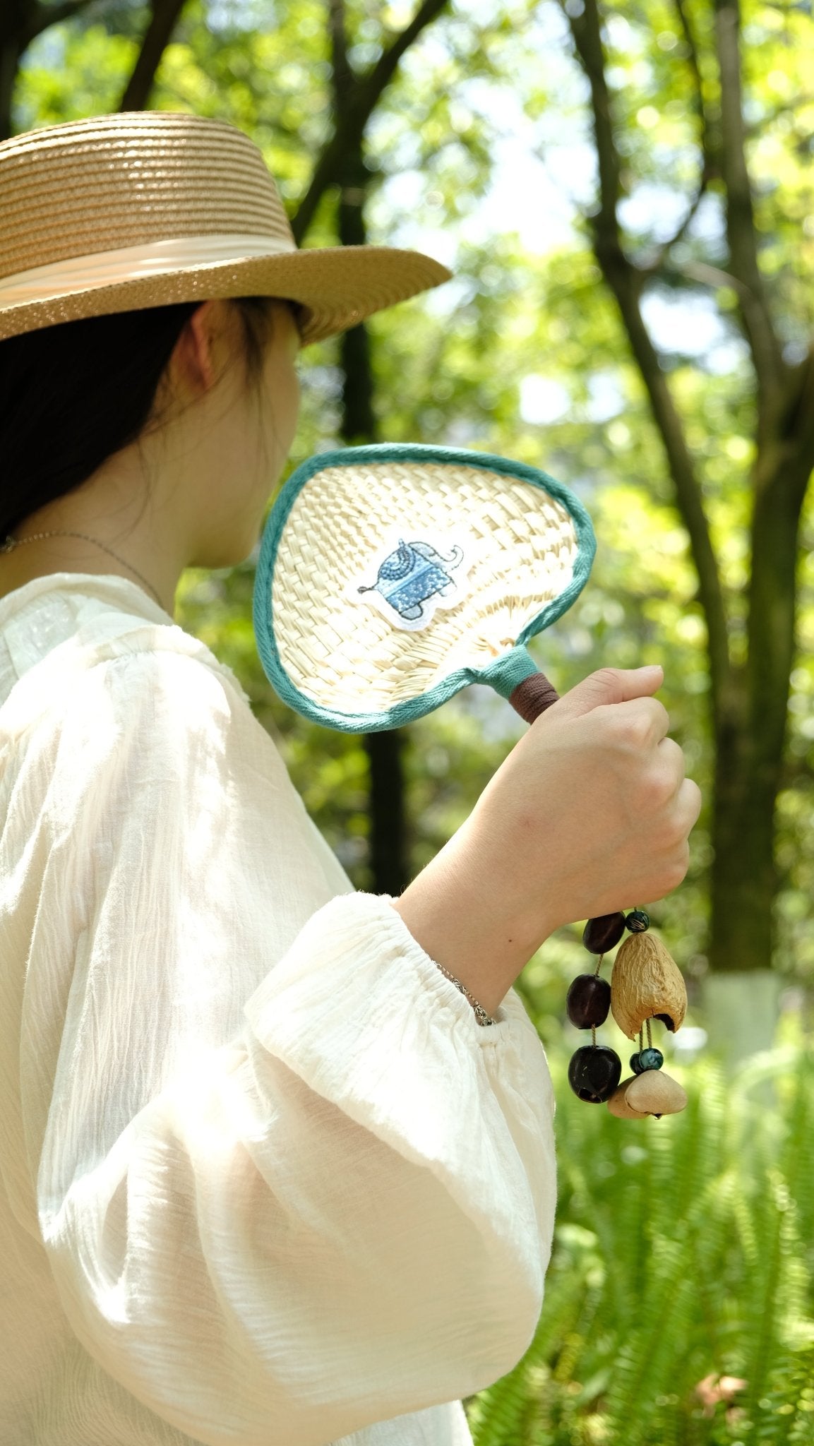The Lucky Breeze - Hand-Woven Heart Palm Fan with Blue Elephant Charm